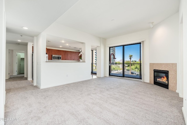 unfurnished living room featuring light colored carpet and a tile fireplace