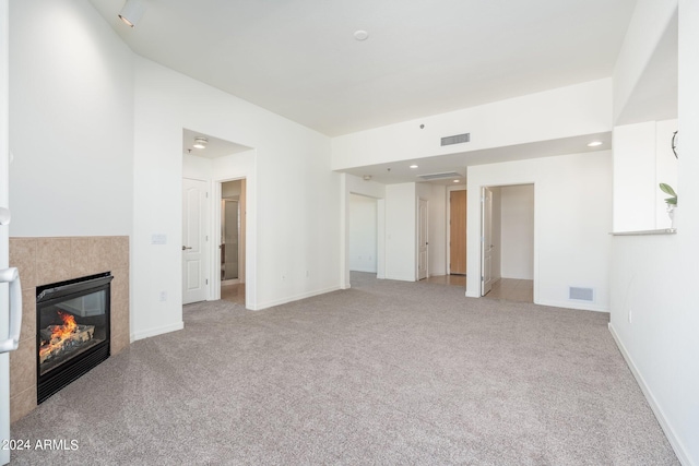 unfurnished living room with a tile fireplace and carpet