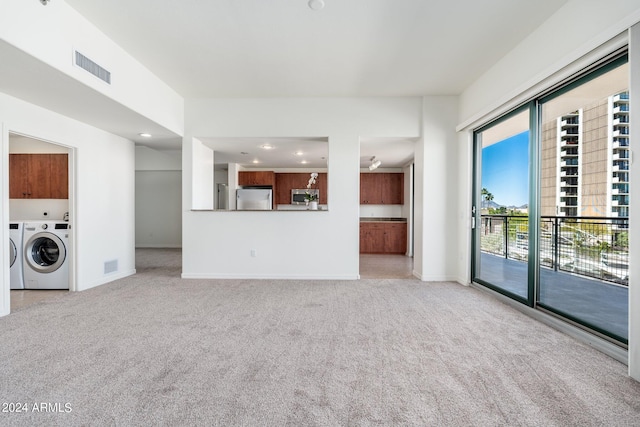 unfurnished living room with independent washer and dryer and light colored carpet