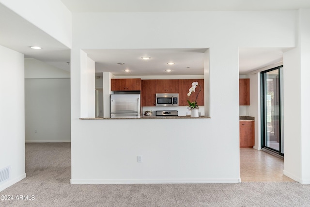 kitchen with light carpet, stainless steel appliances, and light stone countertops