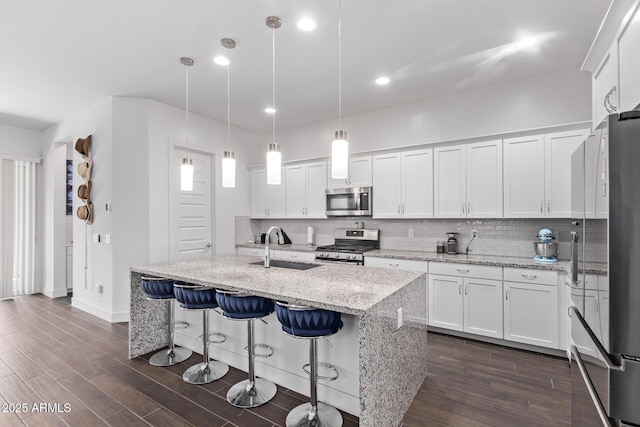 939 E Paseo Way, Phoenix, AZ 85042 - kitchen with appliances with stainless steel finishes, a sink, white cabinetry, decorative backsplash, and a kitchen island with sink