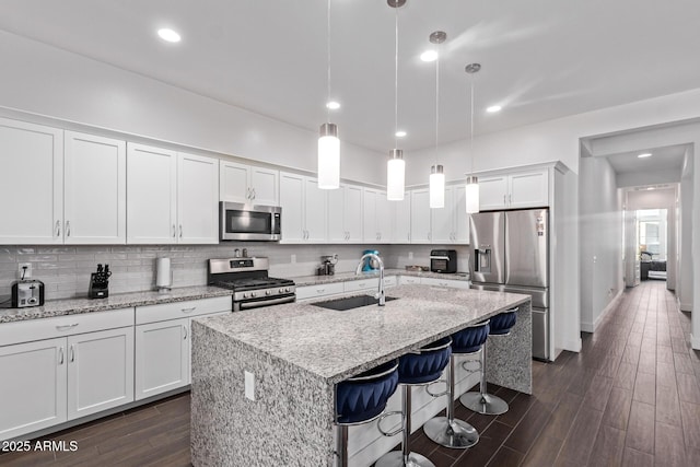 939 E Paseo Way, Phoenix, AZ 85042 - kitchen featuring appliances with stainless steel finishes, a sink, white cabinets, a center island with sink, and a kitchen bar