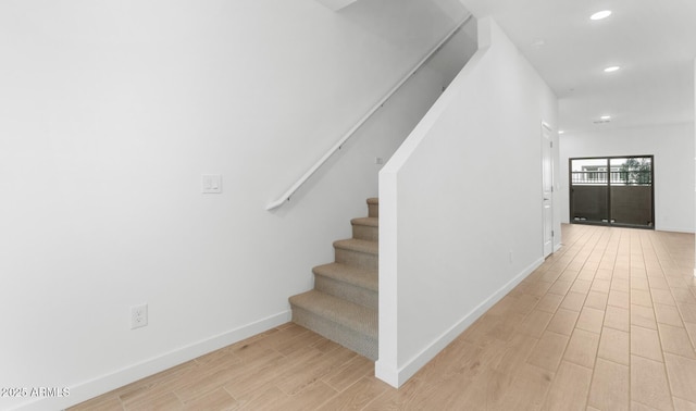 stairs with baseboards, wood finished floors, and recessed lighting