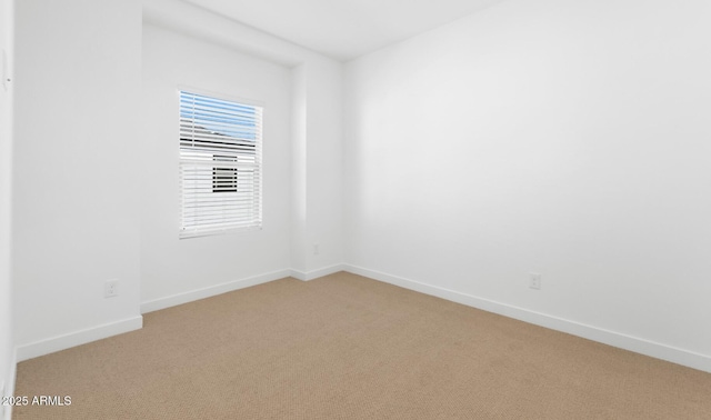 spare room featuring baseboards and light colored carpet