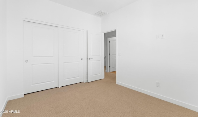 unfurnished bedroom with a closet, light colored carpet, visible vents, and baseboards