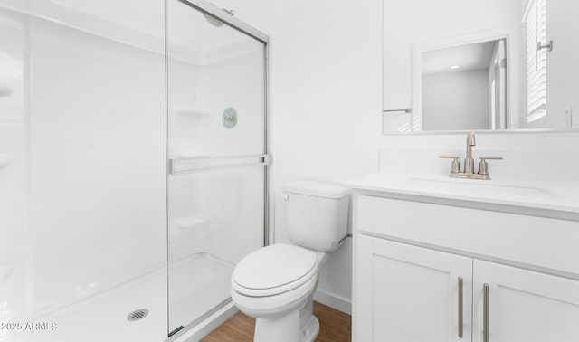 bathroom featuring vanity, a shower stall, toilet, and wood finished floors