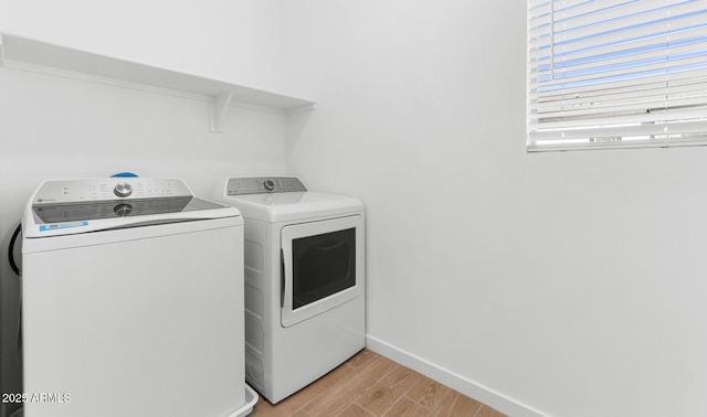 laundry area with light wood-style floors, washing machine and dryer, laundry area, and baseboards