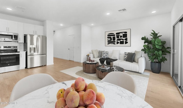 living room featuring light wood-type flooring, visible vents, and recessed lighting