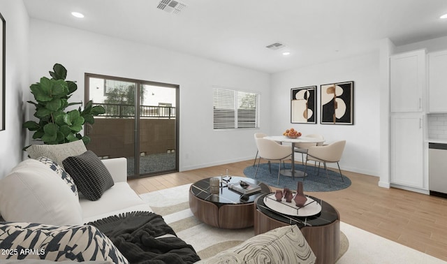 living room featuring light wood-style floors, visible vents, and a healthy amount of sunlight