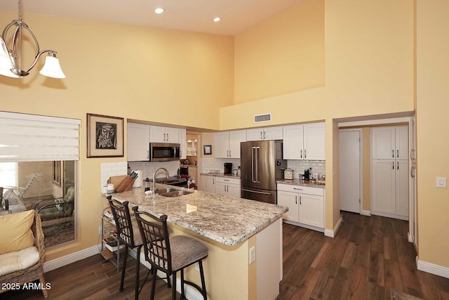 9235 N 101st St, Scottsdale, AZ 85258 - kitchen featuring appliances with stainless steel finishes, a towering ceiling, a peninsula, dark wood-type flooring, and a breakfast bar area