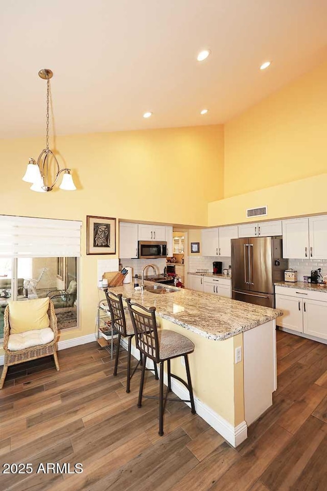 9235 N 101st St, Scottsdale, AZ 85258 - kitchen with appliances with stainless steel finishes, high vaulted ceiling, a peninsula, white cabinetry, and tasteful backsplash