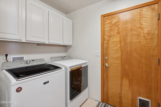 clothes washing area featuring washer and clothes dryer and cabinets