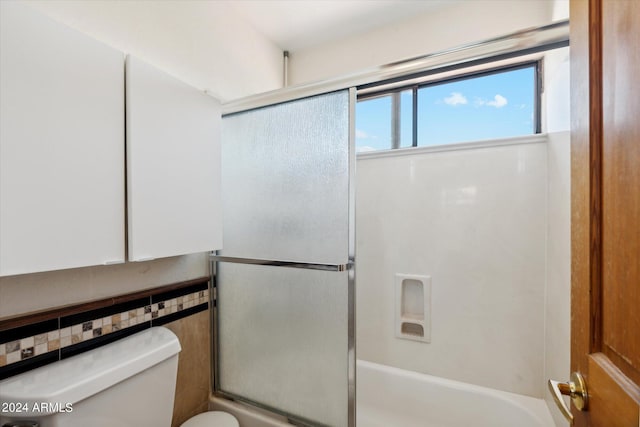 bathroom featuring bath / shower combo with glass door and toilet