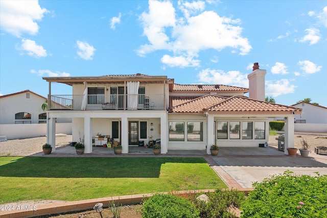 rear view of property featuring a yard, a patio area, and a balcony