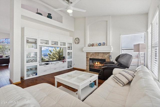 living room featuring ceiling fan, dark wood-type flooring, and a tile fireplace