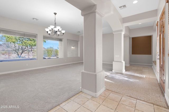 spare room with ornate columns, light colored carpet, and a chandelier