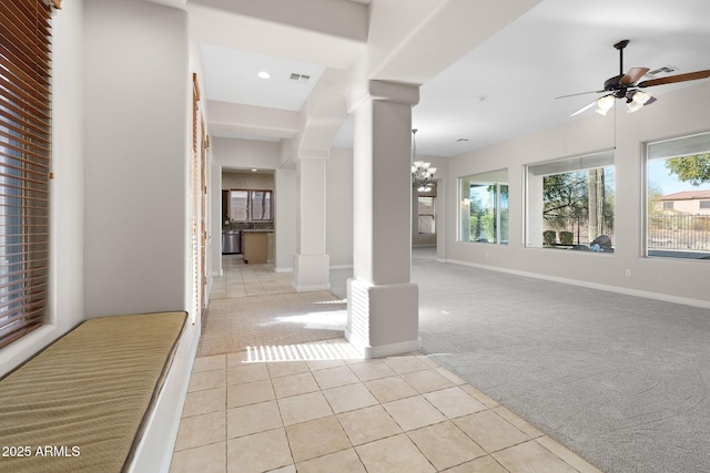 carpeted foyer featuring ceiling fan with notable chandelier and decorative columns