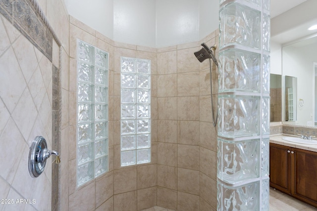 bathroom with tiled shower and vanity