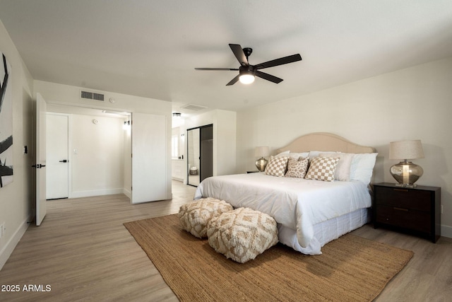 bedroom featuring light wood-type flooring, baseboards, visible vents, and ensuite bath