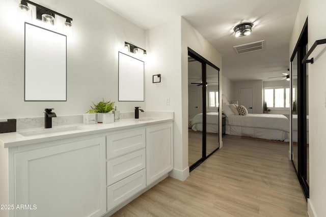 ensuite bathroom with wood finished floors, visible vents, ensuite bathroom, and a sink