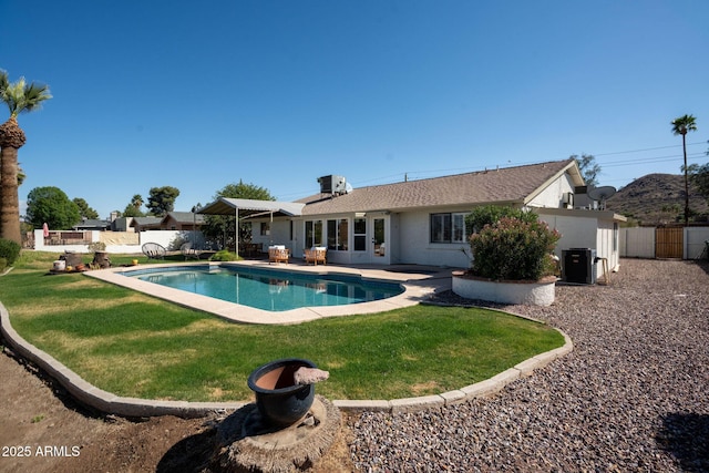 view of swimming pool featuring a lawn, fence, a fenced in pool, central AC unit, and a patio area