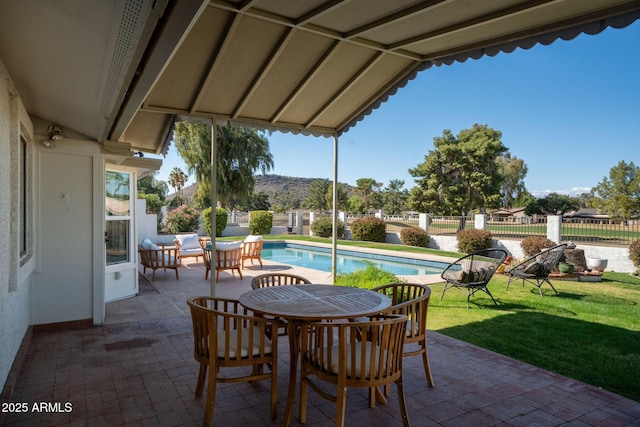 view of patio with a fenced in pool, outdoor dining area, a mountain view, and fence