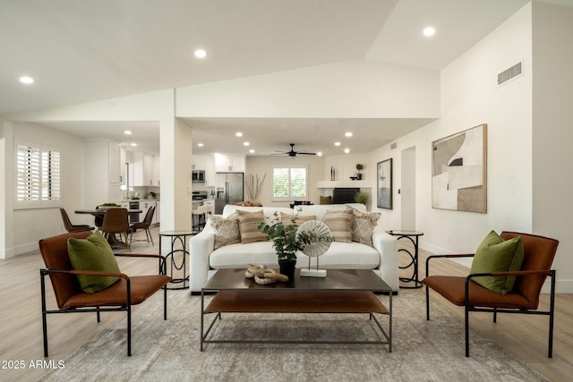 living area featuring vaulted ceiling, visible vents, a wealth of natural light, and light wood-type flooring