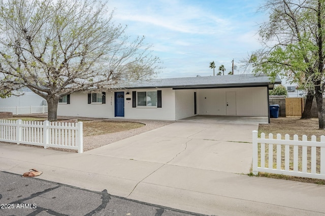 ranch-style home featuring a fenced front yard, an attached carport, and concrete driveway