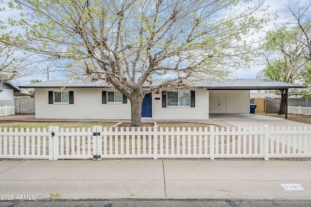 ranch-style house featuring a fenced front yard, an attached carport, and concrete driveway