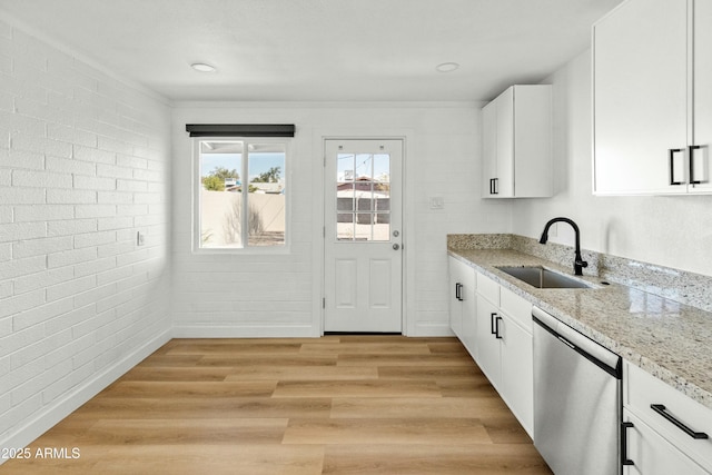 kitchen with sink, white cabinetry, light stone counters, light hardwood / wood-style flooring, and stainless steel dishwasher