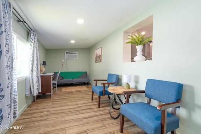 living area with a wall mounted air conditioner and light hardwood / wood-style floors