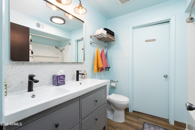 bathroom featuring walk in shower, wood-type flooring, toilet, decorative backsplash, and vanity