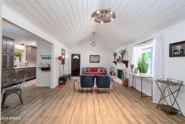 interior space with sink, vaulted ceiling, light hardwood / wood-style floors, a large fireplace, and wood ceiling