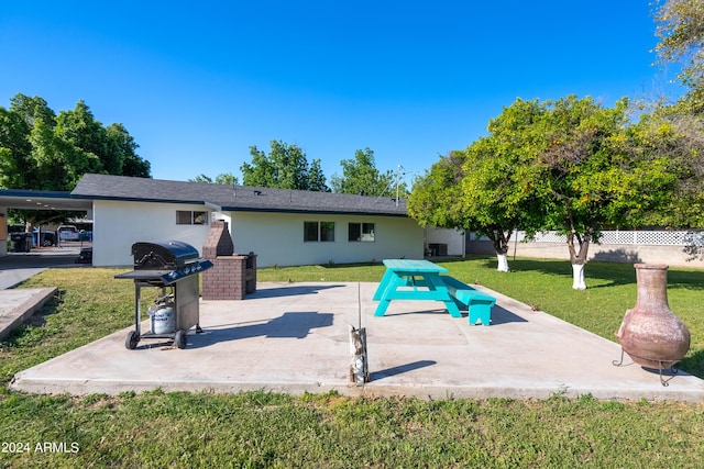 rear view of property with a carport, a patio area, and a lawn