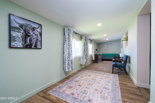 sitting room featuring an AC wall unit and wood-type flooring