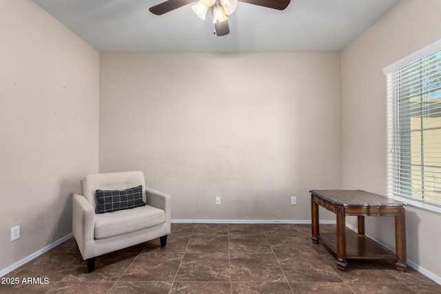 living area featuring a ceiling fan and baseboards