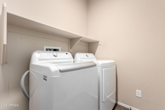 clothes washing area with baseboards, washing machine and dryer, and laundry area