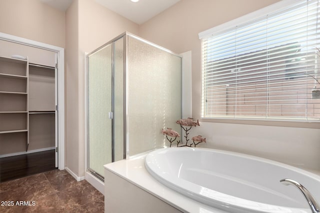 full bathroom with a spacious closet, a garden tub, and a shower stall