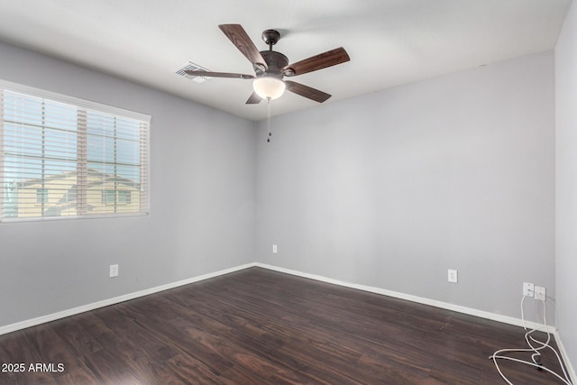 spare room featuring dark wood finished floors, visible vents, baseboards, and ceiling fan