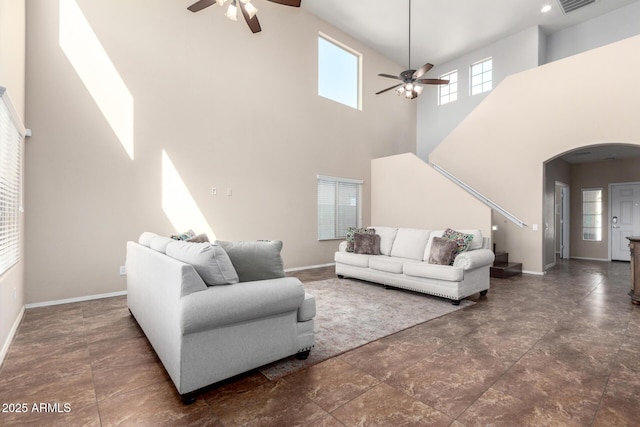 living room with baseboards, visible vents, arched walkways, and ceiling fan