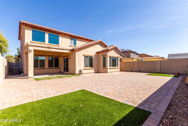 back of property with a fenced backyard, central air condition unit, stucco siding, and a patio