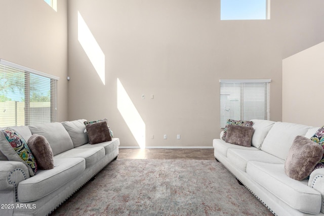 carpeted living area featuring a towering ceiling, a skylight, and baseboards