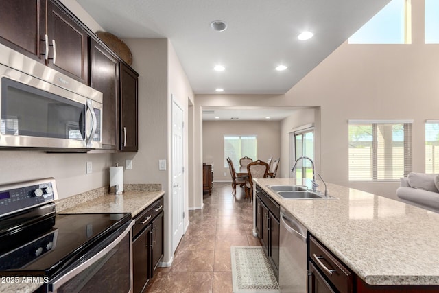 kitchen featuring a sink, appliances with stainless steel finishes, open floor plan, recessed lighting, and dark brown cabinets