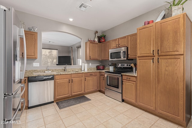 kitchen with light stone countertops, sink, and stainless steel appliances