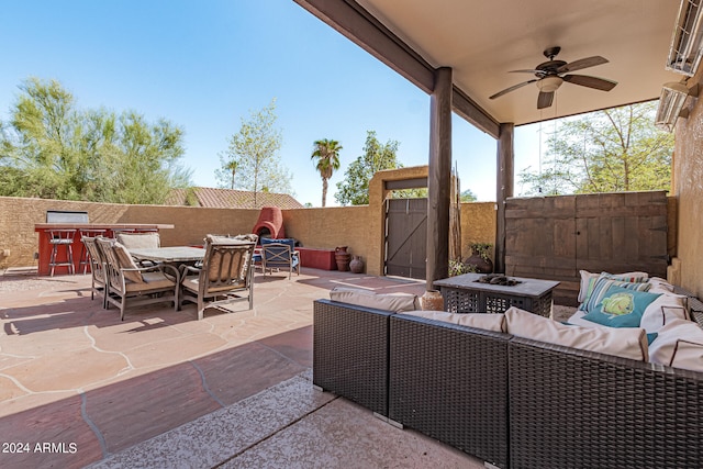 view of patio with ceiling fan and an outdoor living space with a fire pit