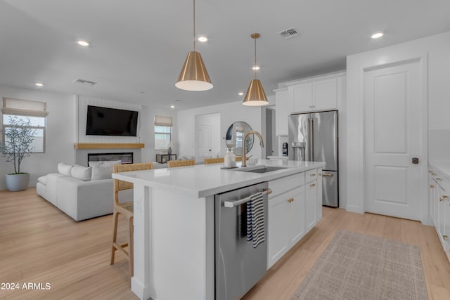 kitchen featuring sink, a center island with sink, appliances with stainless steel finishes, pendant lighting, and white cabinets