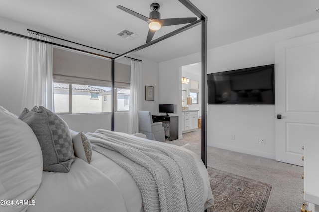 bedroom with light colored carpet, ceiling fan, and ensuite bath