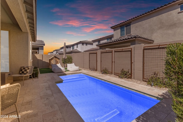 pool at dusk with a patio area