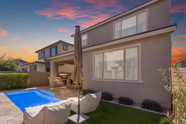 back house at dusk with a fenced in pool and a patio