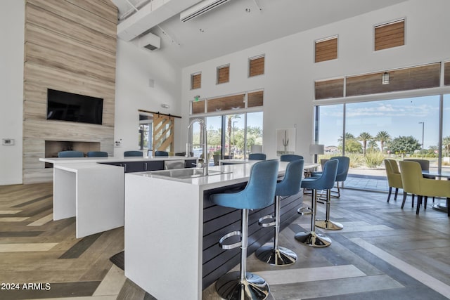 kitchen featuring a kitchen island with sink, parquet flooring, a barn door, and a high ceiling